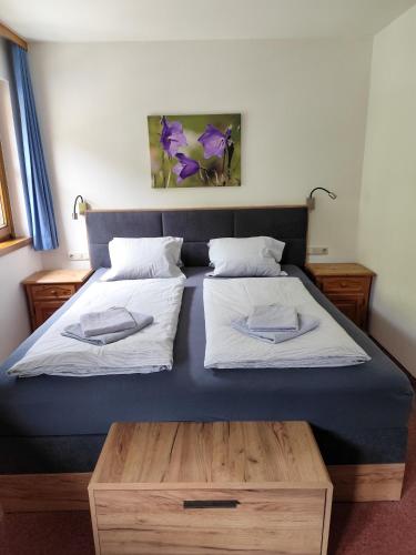 a bedroom with two beds and a wooden table at Appartements Haus am Römerbad Bad Kleinkirchheim in Bad Kleinkirchheim