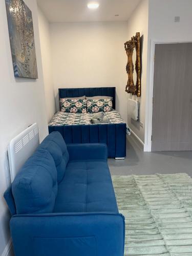 a living room with a blue couch and a bed at Cosy flat in central Cardiff Bay in Cardiff