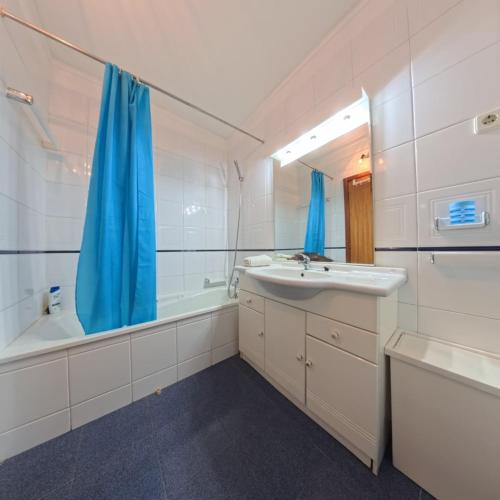 a bathroom with a sink and a blue shower curtain at Cavado Pool Apartment in Fão