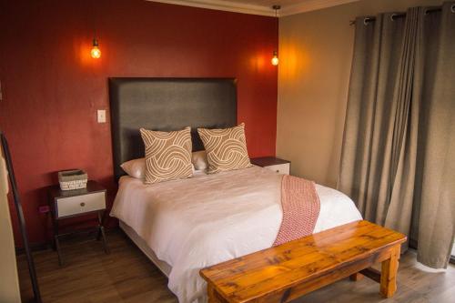 a bedroom with a bed with a wooden bench on it at Benedicto Farm in Welkom