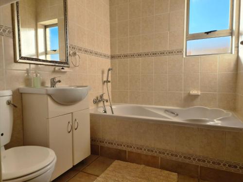 a bathroom with a tub and a sink and a toilet at Kleinmond Panorama Holidays in Kleinmond