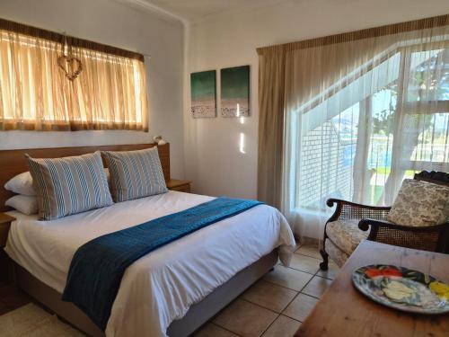 a bedroom with a bed and a chair and a window at Kleinmond Panorama Holidays in Kleinmond
