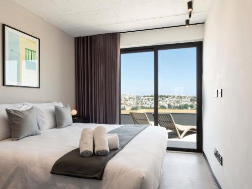 a bedroom with a large white bed with a balcony at Aparthotel Adagio Malta Central in Msida