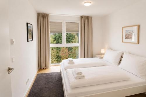 a white bedroom with two beds and a window at Danube Suites in Vienna