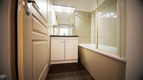 a small bathroom with a sink and a door at Résidence Goélia An Douar in Audierne