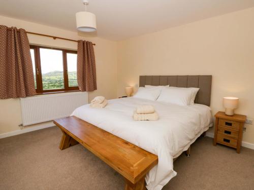 a bedroom with a large white bed and a wooden table at Yr Onnen in Rhayader