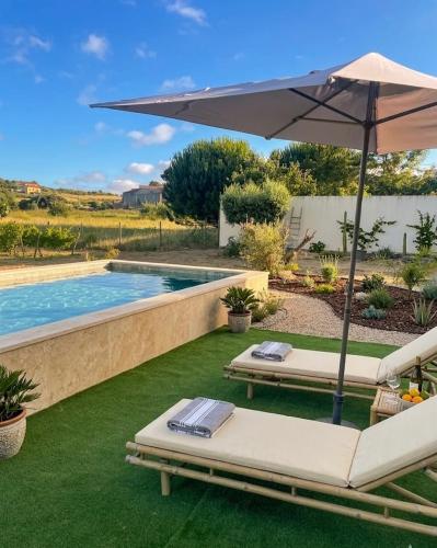 two lounge chairs and an umbrella next to a swimming pool at Maçussa Country House in Massuça
