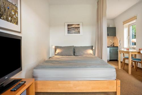 a bedroom with a bed and a desk with a television at Mohnrot - Fulgenhaus in Klein Bollhagen