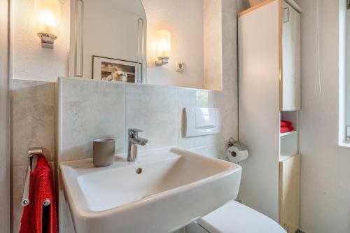 a white bathroom with a sink and a toilet at Mohnrot - Fulgenhaus in Klein Bollhagen