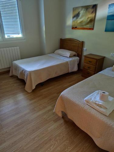 a bedroom with two beds and a wooden floor at O marco da legua&camino de santiago in Piñor