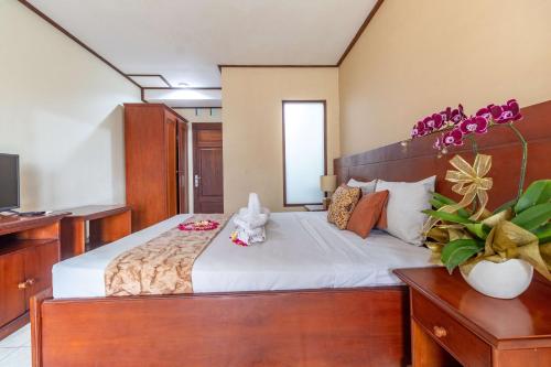a bedroom with a large bed with white sheets at Maha Jaya Hotel Bali in Denpasar