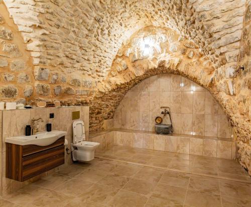 a stone bathroom with a sink and a toilet at Rocinante House in Mardin