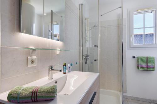 a white bathroom with a sink and a shower at La Barbâtrine in Barbâtre