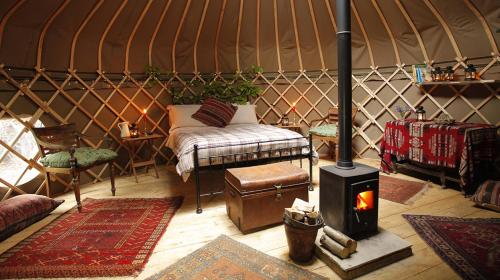 a yurt with a bed and a stove in it at Adhurst Yurts in Sheet