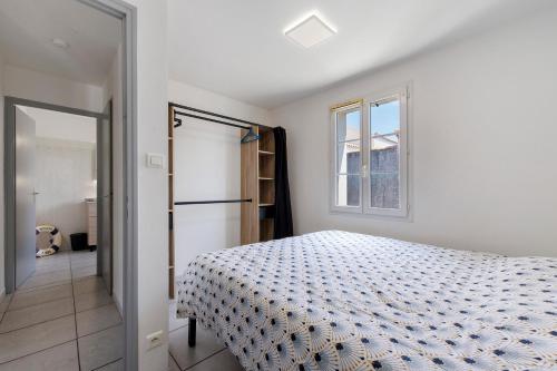 a white bedroom with a bed and a window at La Barbâtrine in Barbâtre