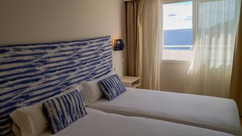 a bedroom with a bed and a window with the ocean at Blau Punta Reina in Cala Mendia