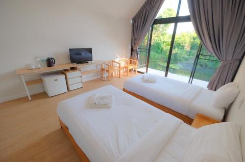 a hotel room with two beds and a television at พฤกษา วัลเลย์ รีสอร์ท in Ban Mak