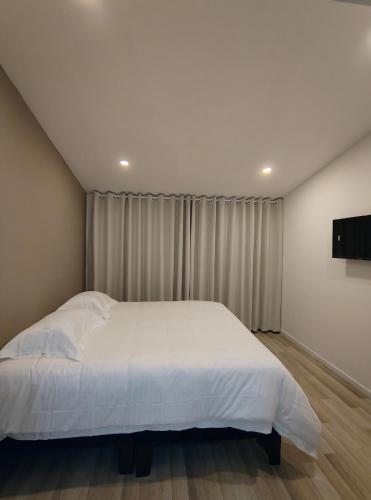 a bedroom with a white bed and a curtain at Andes 97 Guest House in Bogotá