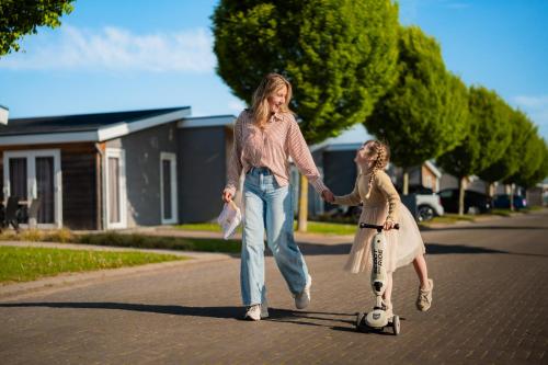 a woman and a girl riding a scooter down a street at Resort Mooi Bemelen in Bemelen