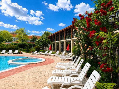 a group of white lounge chairs next to a pool at Hotel Jupiter in Sunny Beach