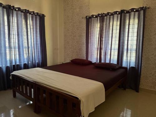 a bed in a bedroom with windows with curtains at The Mystery palace in Varkala