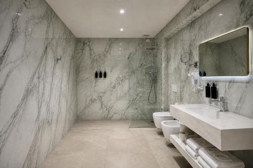 a marble bathroom with a sink and a toilet at Lh HOTELS in Milan