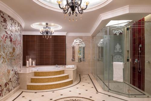 a bathroom with a bath tub and a chandelier at Marsa Malaz Kempinski, The Pearl in Doha