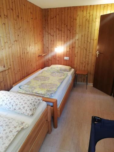 two beds in a room with wooden walls at Alb-Refugium - beautiful, quiet in Schopfloch