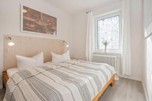 a white bedroom with a bed with a striped blanket at Ferienanlage Seeblick Kunstquartier in Koserow