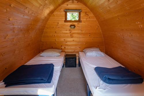 two beds in a log cabin with a window at Camping Onlycamp le Clos Imbert in Thouars