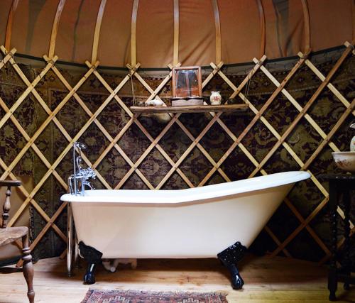 a white bath tub in a room with a wall at Adhurst Yurts in Sheet