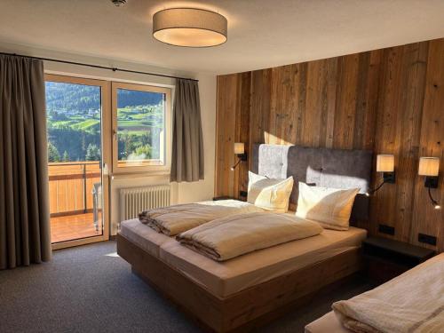 a bedroom with a bed and a large window at Alpenresort Panorama in Oberperfuss