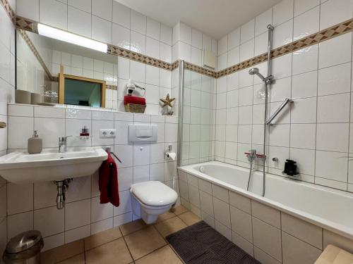 a bathroom with a sink and a toilet and a tub at Oewern Diek App 03 in Wustrow
