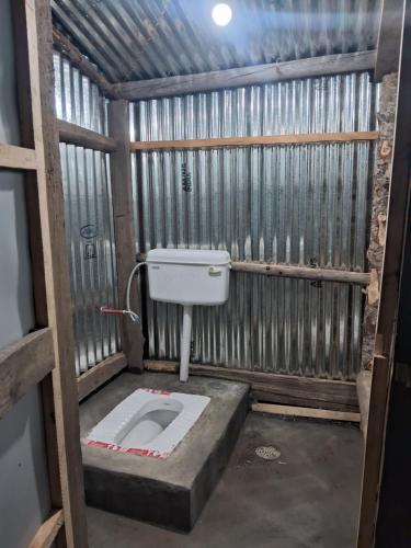 a bathroom with a toilet in a metal building at TIS Zipline Campingsite in Gurais