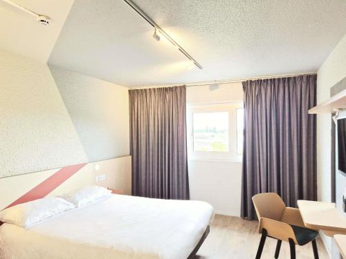a hotel room with a bed and a desk and a window at ibis budget Tours Sud in Chambray-lès-Tours