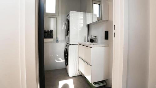 a white kitchen with a refrigerator and a sink at TheSnoozzze Boardinghouse Winsen - Monteur Apartments in Winsen