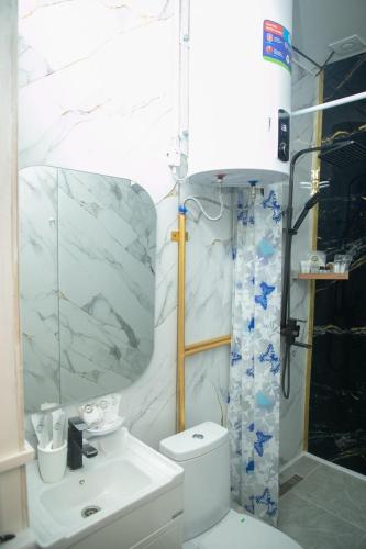 a white bathroom with a toilet and a sink at Ethno Naryn Guest House in Naryn