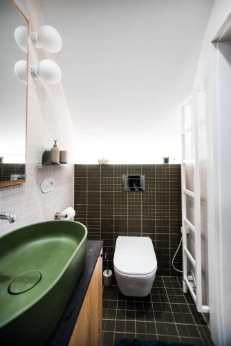 a bathroom with a green tub and a toilet at Domek nad jeziorem z jacuzzi ROMANTICA in Wilamowo