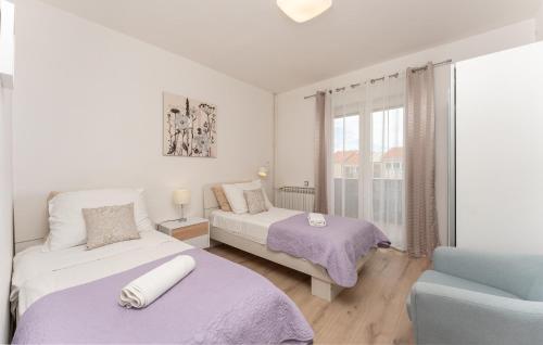 a bedroom with two beds and a chair and a window at Olive Dreams in Biograd na Moru