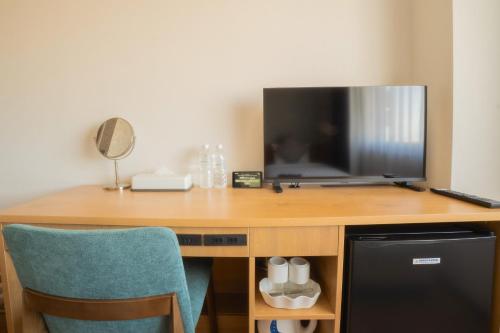 a desk with a television and a blue chair at Osaka Kansai Airport Hotel Kansai Airport 2 station in Izumi-Sano