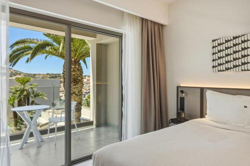 a bedroom with a bed and a balcony with a table at Scala Boutique Hotel & Suites - Adults Only in Agia Pelagia