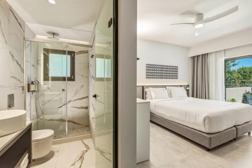 a bedroom with a king sized bed and a shower at Scala Boutique Hotel & Suites - Adults Only in Agia Pelagia