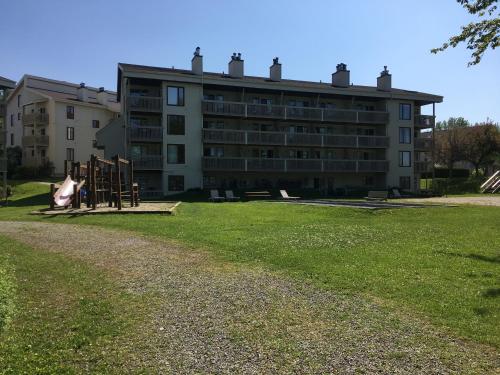 an apartment building with a playground in front of it at Au p'tit cocon sur le lac in Magog-Orford
