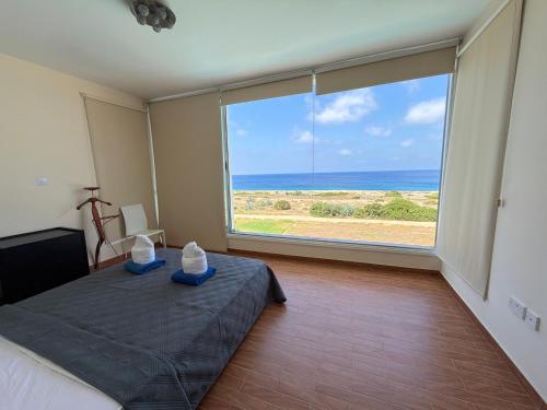 a bedroom with a large window with a view of the ocean at Nireas Crystal in Aglantzia