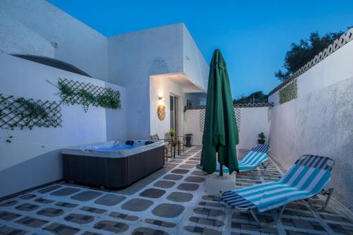 a patio with a tub and two chairs and a umbrella at CASA MIKELE by Sarikas - SEA SIDE SUITES and STUDIOS -adults only in Faliraki
