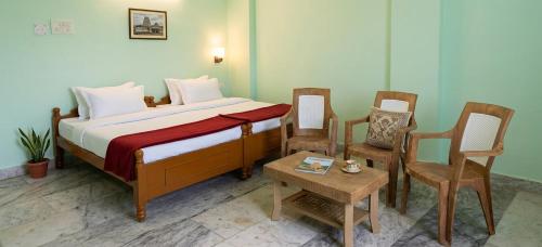 a bedroom with a bed with two chairs and a table at Sri lucky grand lodge and function hall in Raigīr