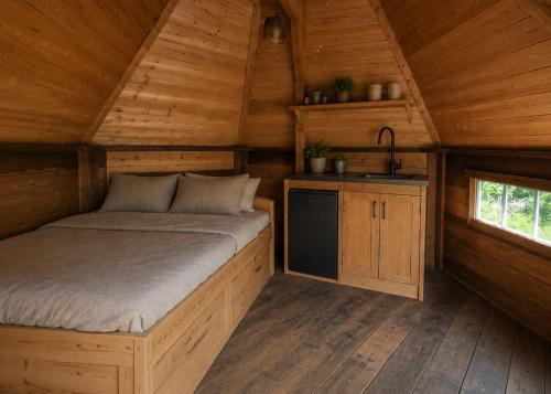 Ein Schlafzimmer in einer Holzhütte mit Bett und Waschbecken in der Unterkunft Tinyhouse De Einder in Pieterburen