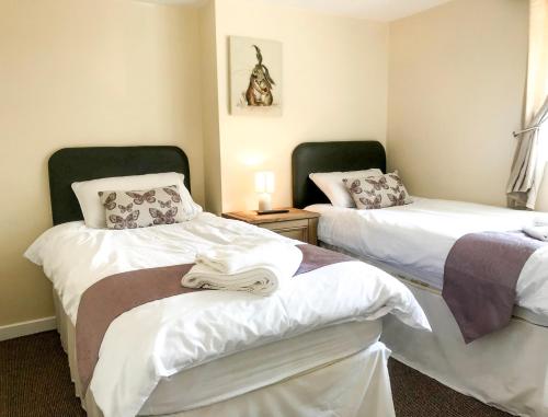 a room with two beds with white sheets at Brewery Lodge Sleeps 4 in Lydney
