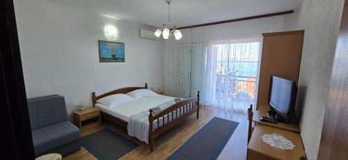 a bedroom with a bed and a television and a couch at Karmen 2 in Sveti Juraj