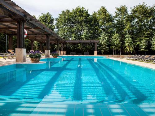 a large swimming pool with a pergola at Mercure Palanga Vanagupe Resort & SPA in Palanga